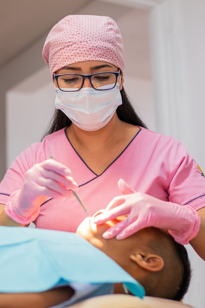 gallery-5 A dentist in pink uniform examining a patient's teeth, focusing on dental care.