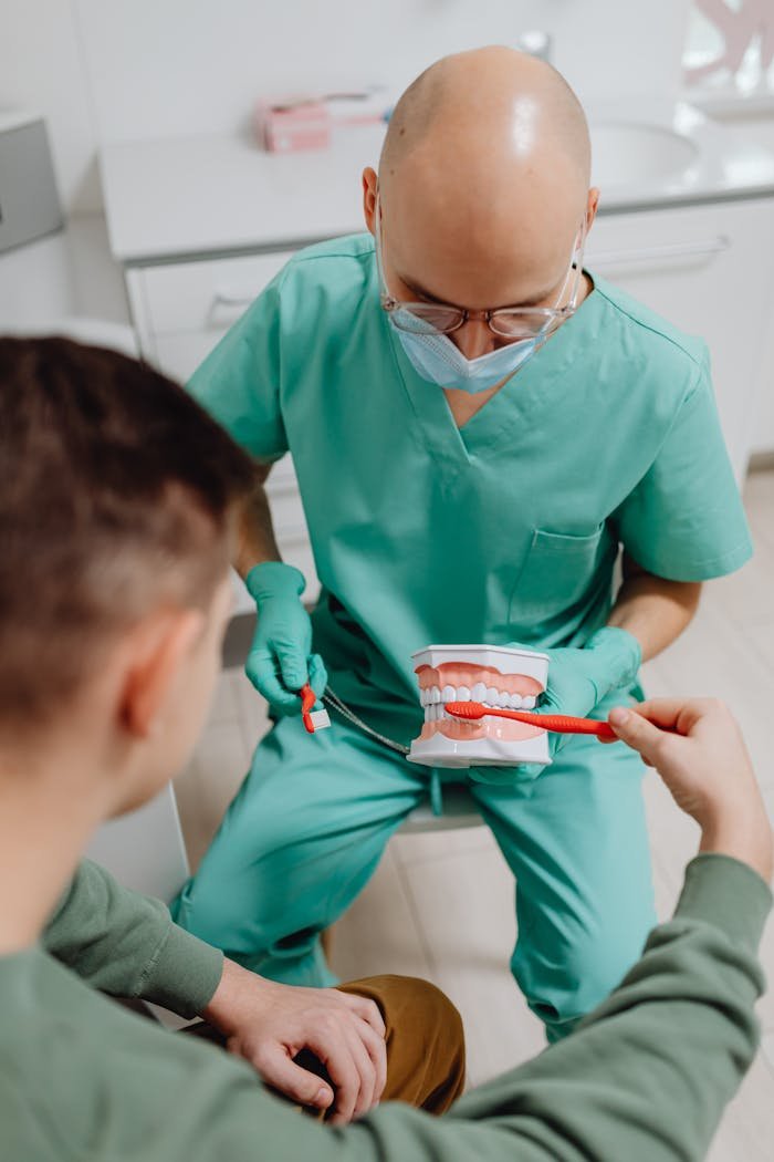 why-choose-us Dentist shows patient proper brushing techniques using a dental model in a clinical setting.
